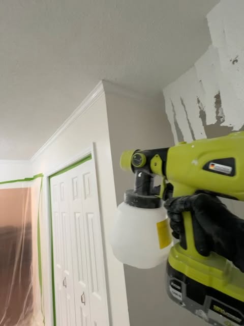 Painter spraying paint with the room taped off